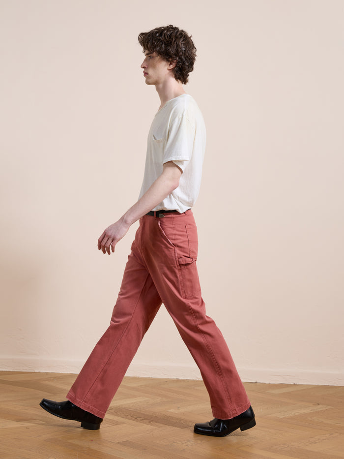 A person wears FOUND Canvas Faded Pants and a white t-shirt while walking indoors on a wooden floor against a plain light-colored wall.
